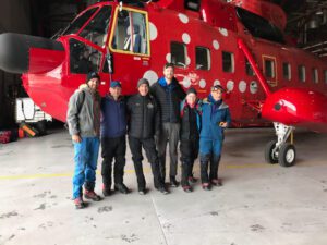 People standing in front of a red helicopter.