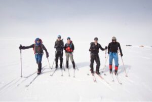 Five people in snow, posing for a photo.