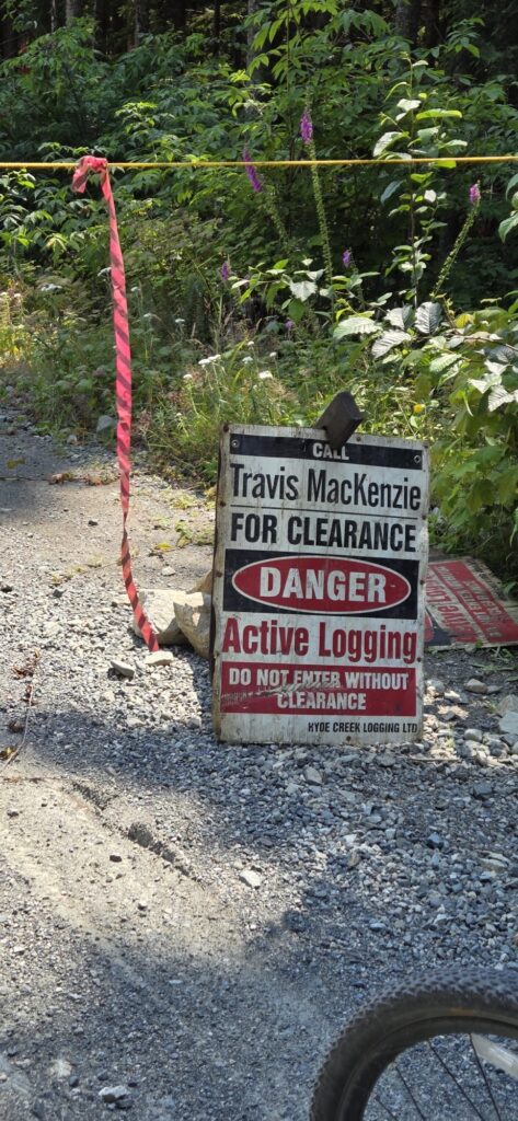 Warning sign beside a forest road advising travellers to call for clearance before entering an area of active logging operations.